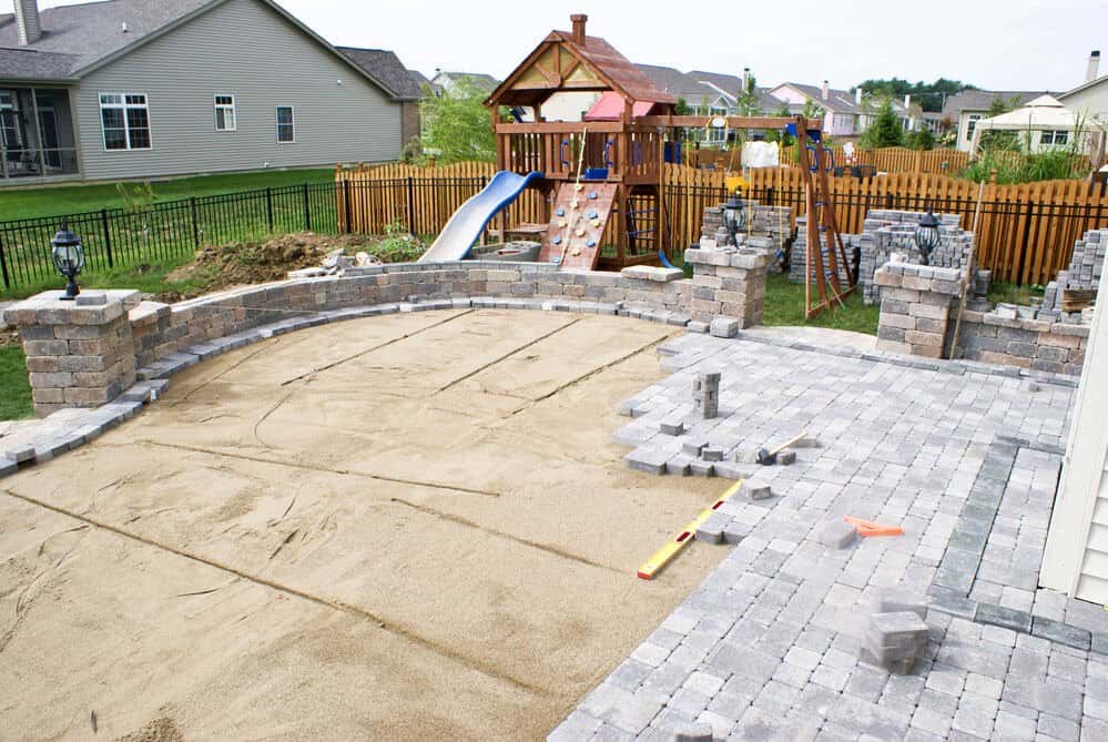 Sherman Oaks, CA 1 Backyard patio under construction with gray pavers, playground set, and wooden fence