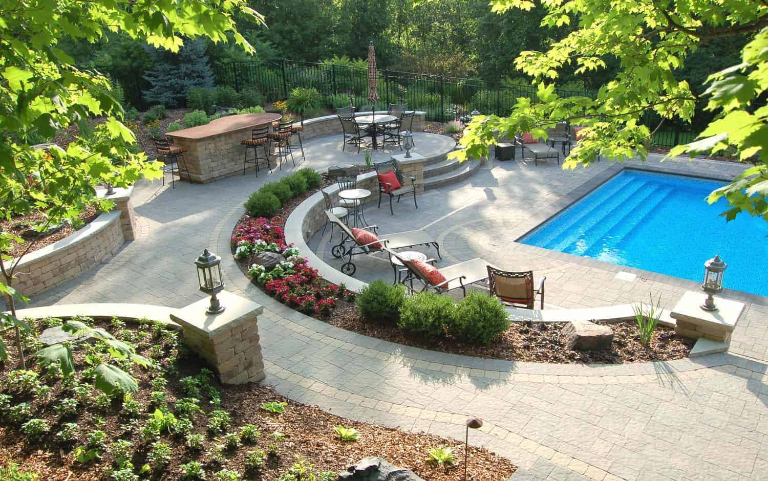 Landscaped backyard with patio, seating area, and rectangular pool surrounded by trees