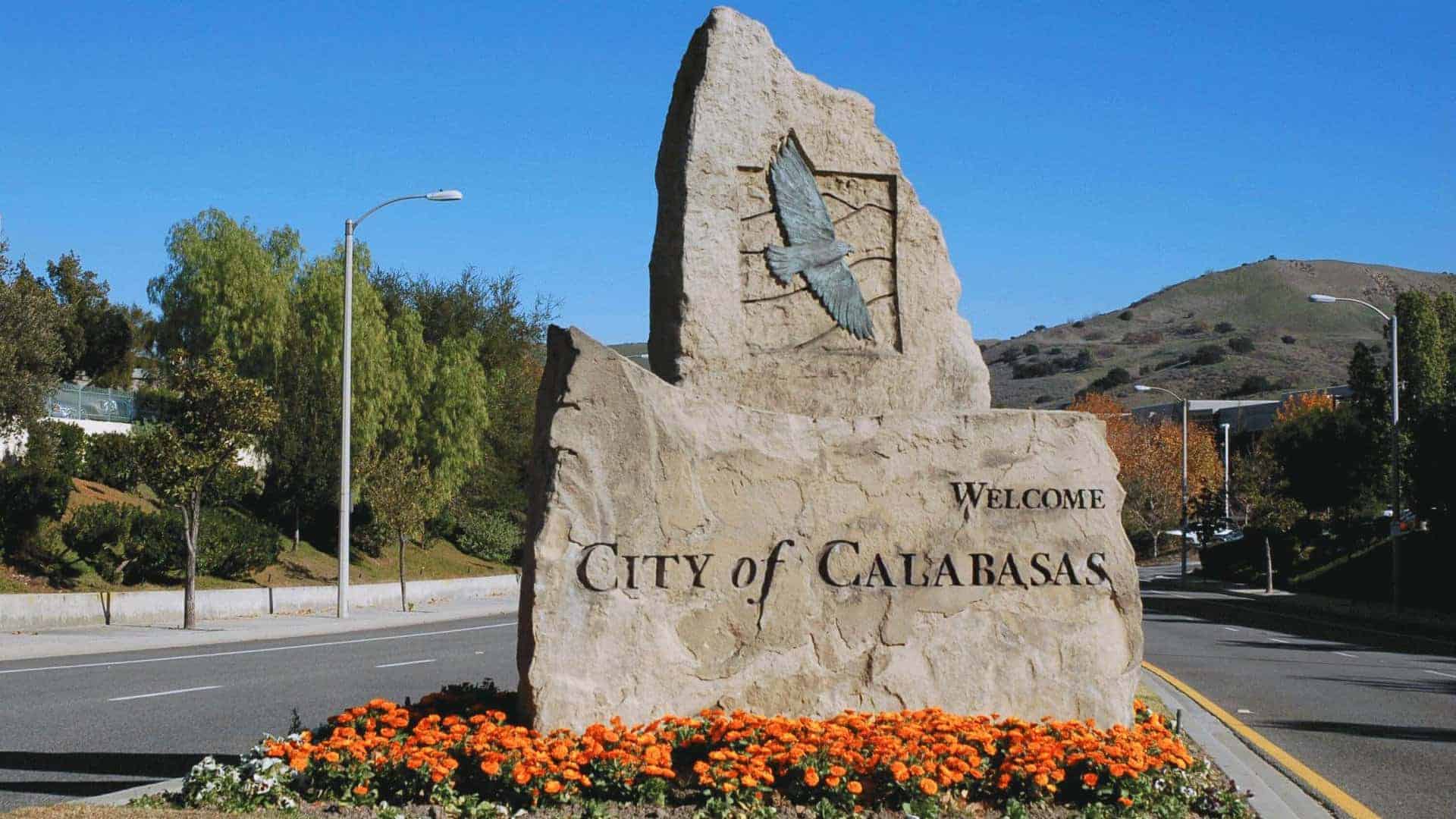 Calabasas, CA 1 Welcome to Calabasas stone monument with metal bird sculpture, orange flowers, and hills
